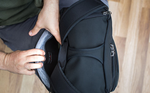 A person holding open the shoulder strap pocket of the Aeronaut with the frame inside